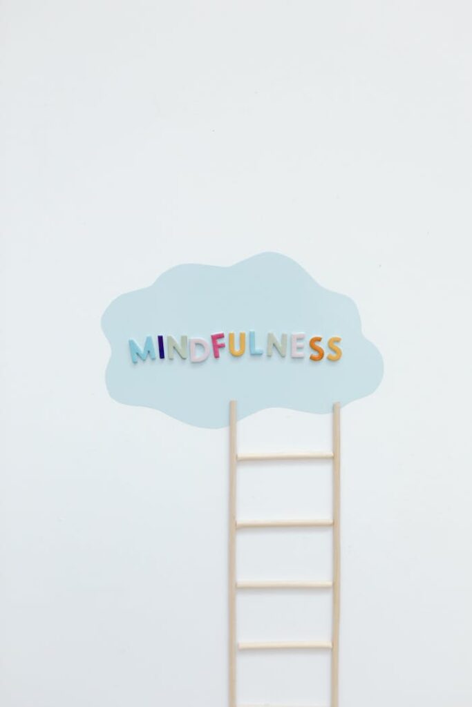 Minimalist image of a ladder leading to a cloud with colorful 'mindfulness' text.